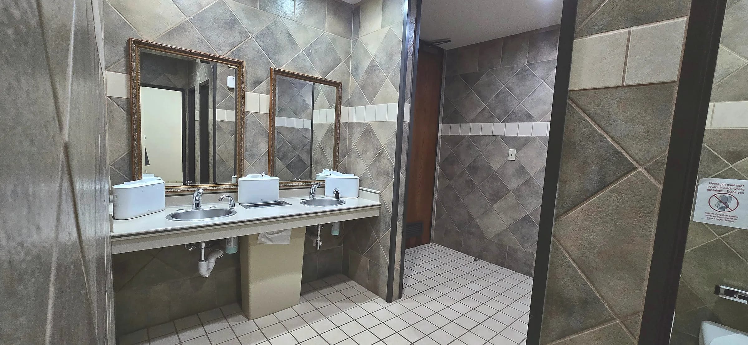 Common restroom with tiled walls and double vanity